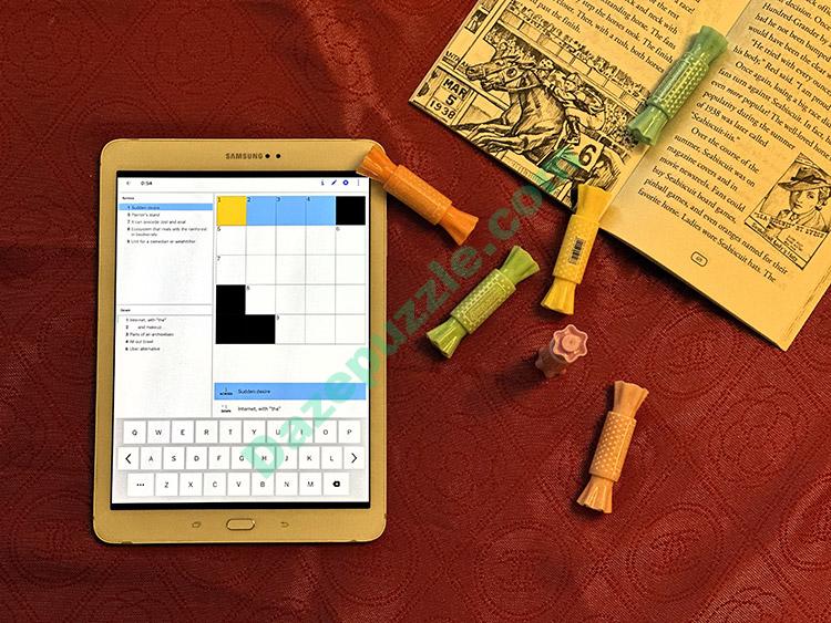 NYT mini crossword light theme tablet alongside book